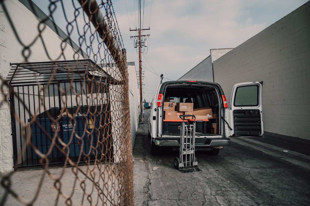 An open van loaded with boxes in an alley, ready for donation deliveries.