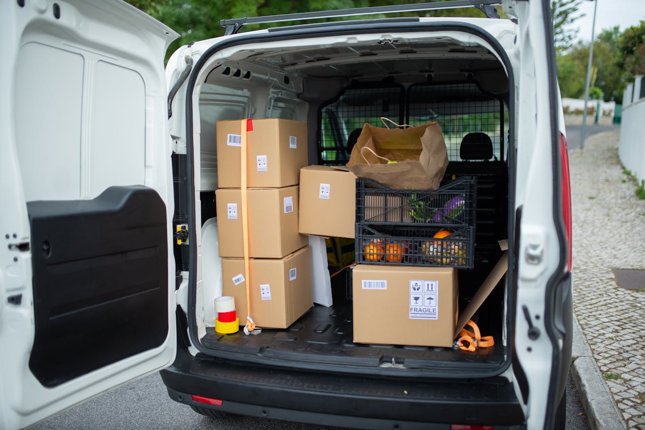 Open delivery van with cardboard boxes and packages on a Portuguese street, showcasing logistics in action.
